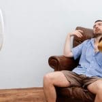 62251979 – flushed man feeling hot in front of a fan