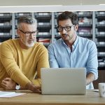 Businessmen using laptop together at desk